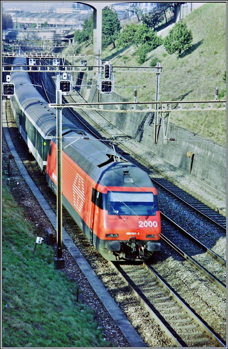 Eine SBB Re 460 auf dem damals noch dreigleisigen Abschnitt kurz nach Lausanne schiebt ihren, damals noch grünen EW IW Zug in Richtung Genève. Heute wird dieser Streckenteil auf vier Gleise ausgebaut. 

Frühjahr 1998