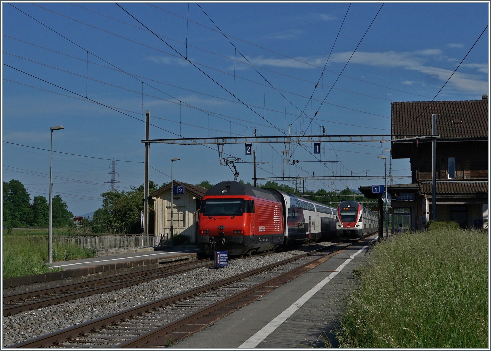 Eine SBB RE 460 mit ihrem IR 90 auf der Fahrt nach Genève und ein SBB RABe 511 aus der Gegenrichtung in Roches VD. 

12. Mai 2022