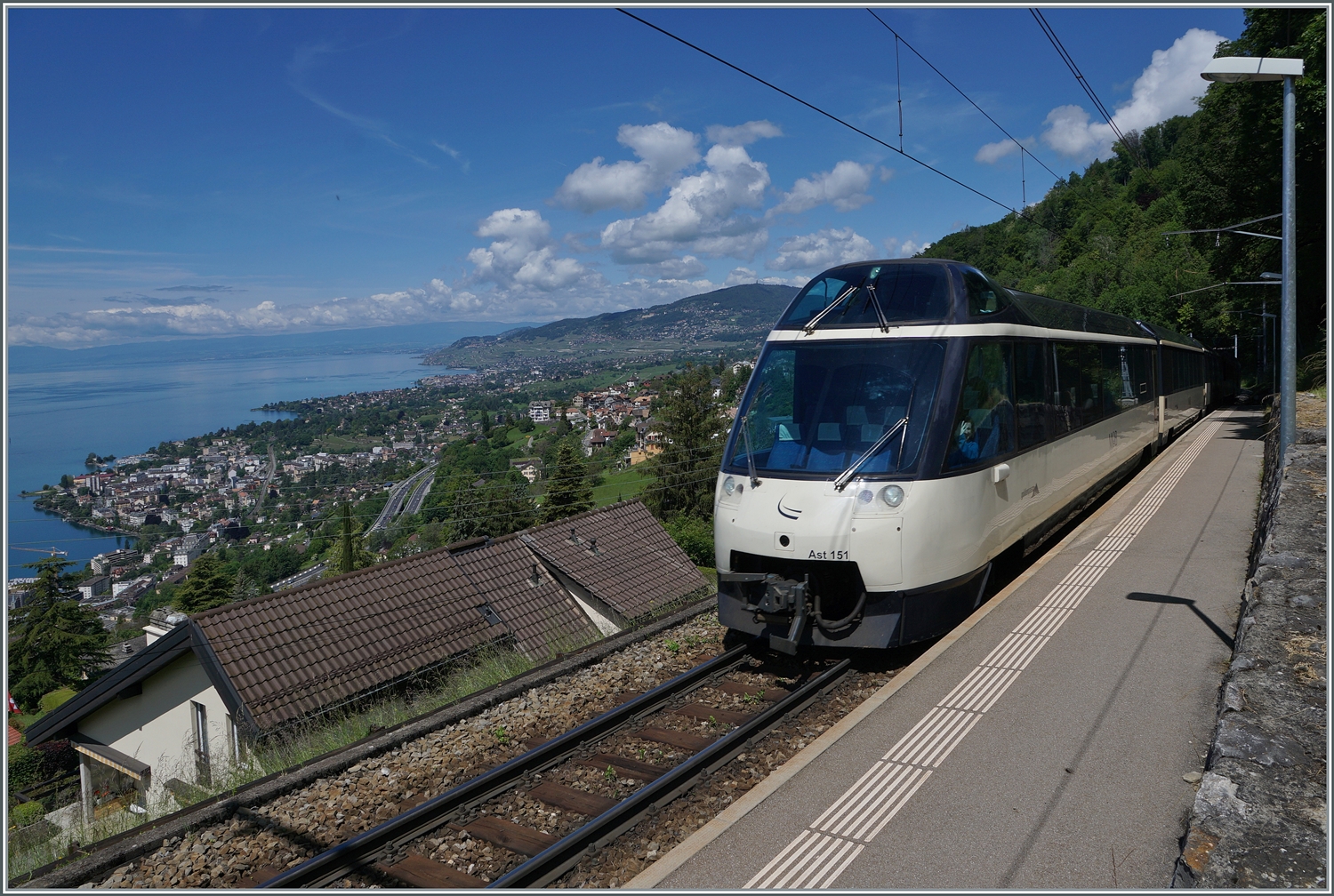 Noch mehr Panorama bietet (dank Weitwinkel) dieses Bild Mit dem Ast 151 an der Spite ist ein MOB Regionalzug von Montreux nach Zweisimmen bei Sonzier unterwegs, während links im Bild der Blick weit über den See, die Riviera Vaudoise und das Lavaux gleitet. 

28. Mai 2024