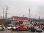 2 rote Fahrzeuge - BR 185 mit einem G�terzug und ein FeuerwehrFahrzeug beim Einsatz am Hallenser Hauptbahnhof am Morgen des 19.11.14